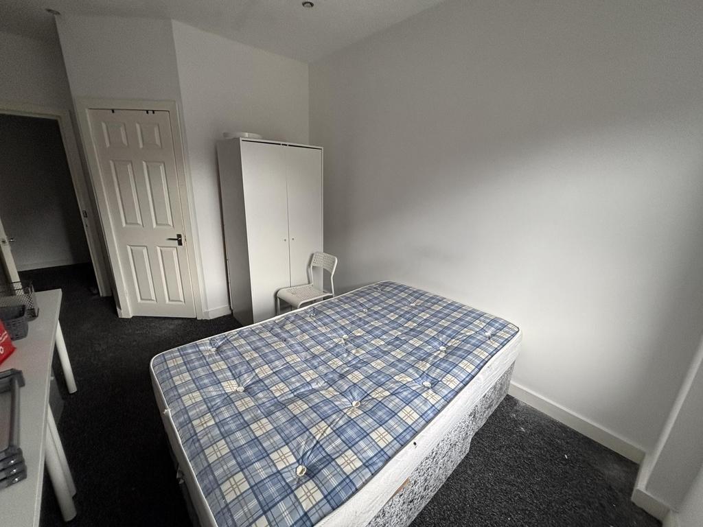 A cozy single bedroom with a simple bed in a br...
