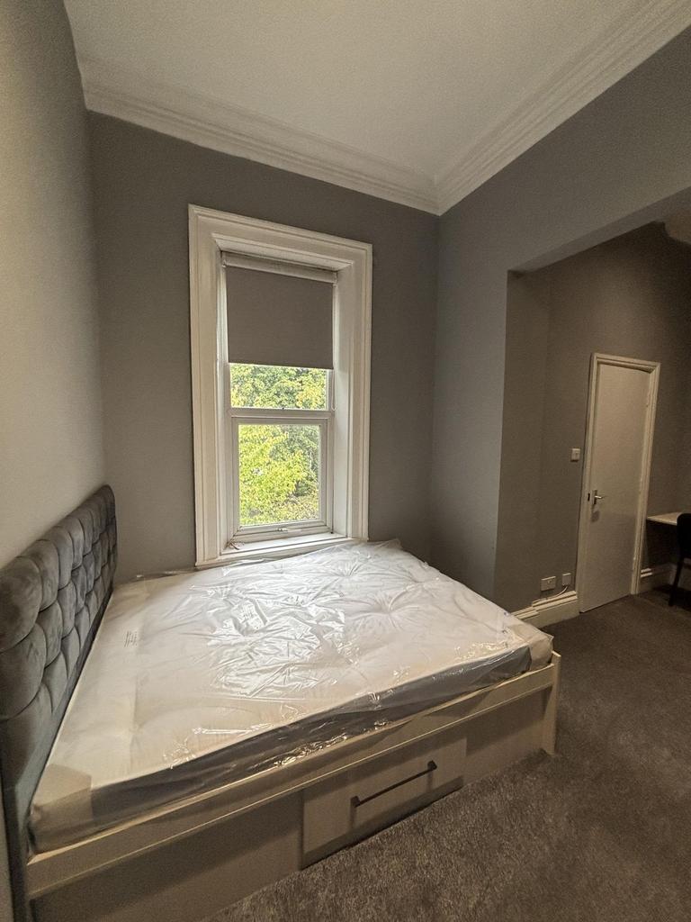 A well-lit double bedroom featuring a comfortab...