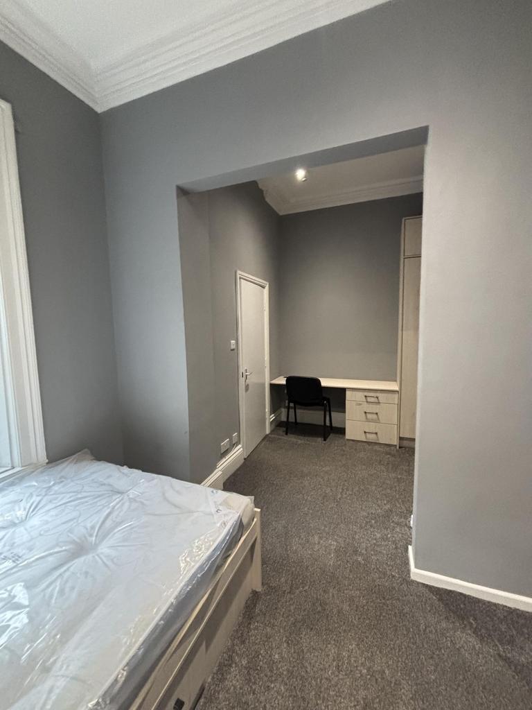 A cozy bedroom with neutral gray walls and a co...