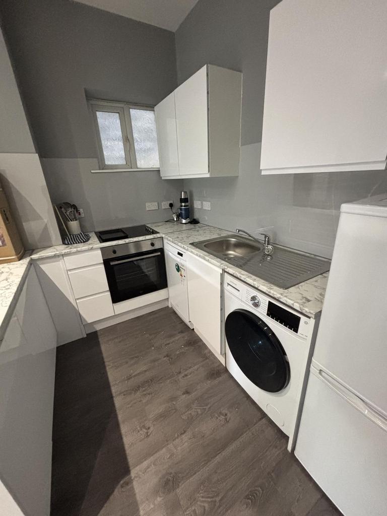 A modern, compact kitchen area featuring white ...