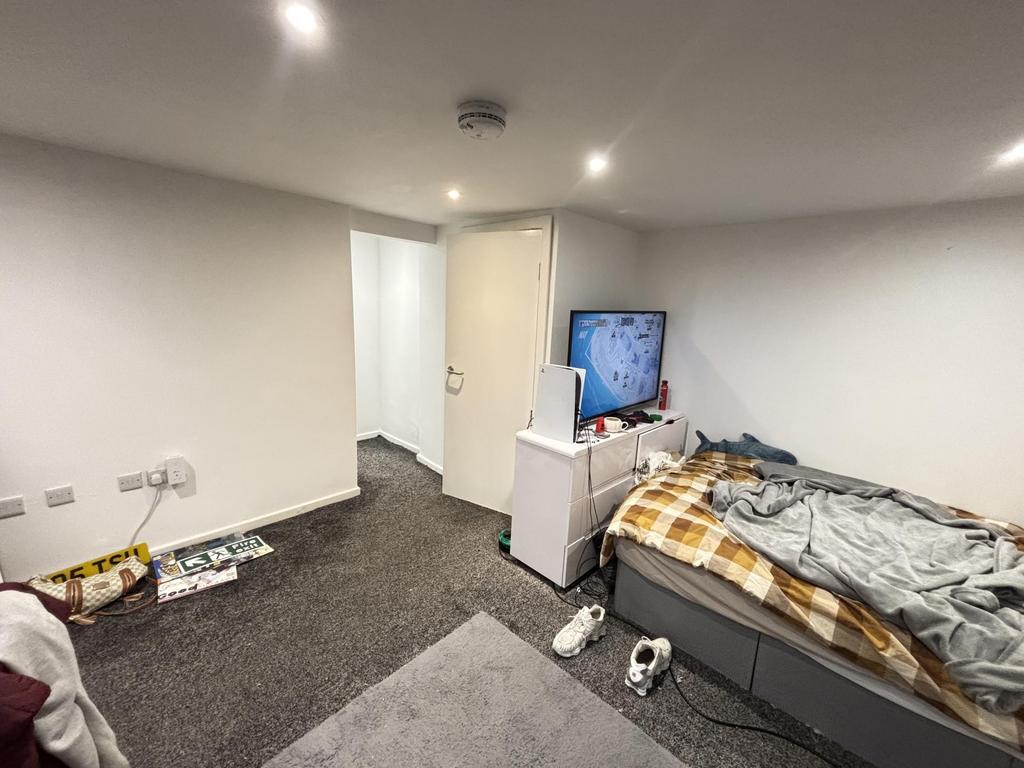 A modest bedroom with a single bed, a TV, and m...