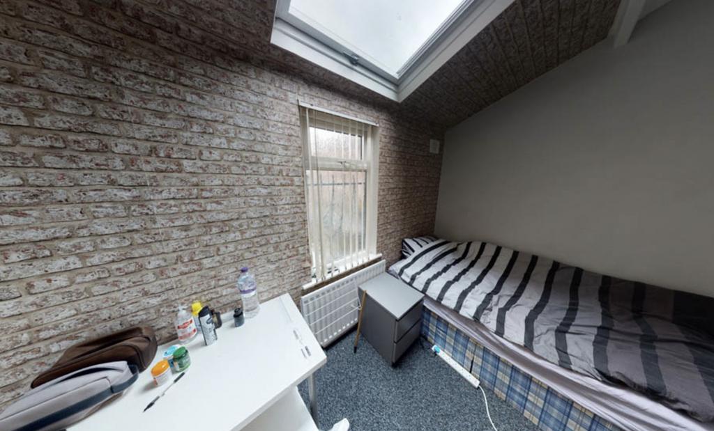 A cozy bedroom featuring a single bed with stri...