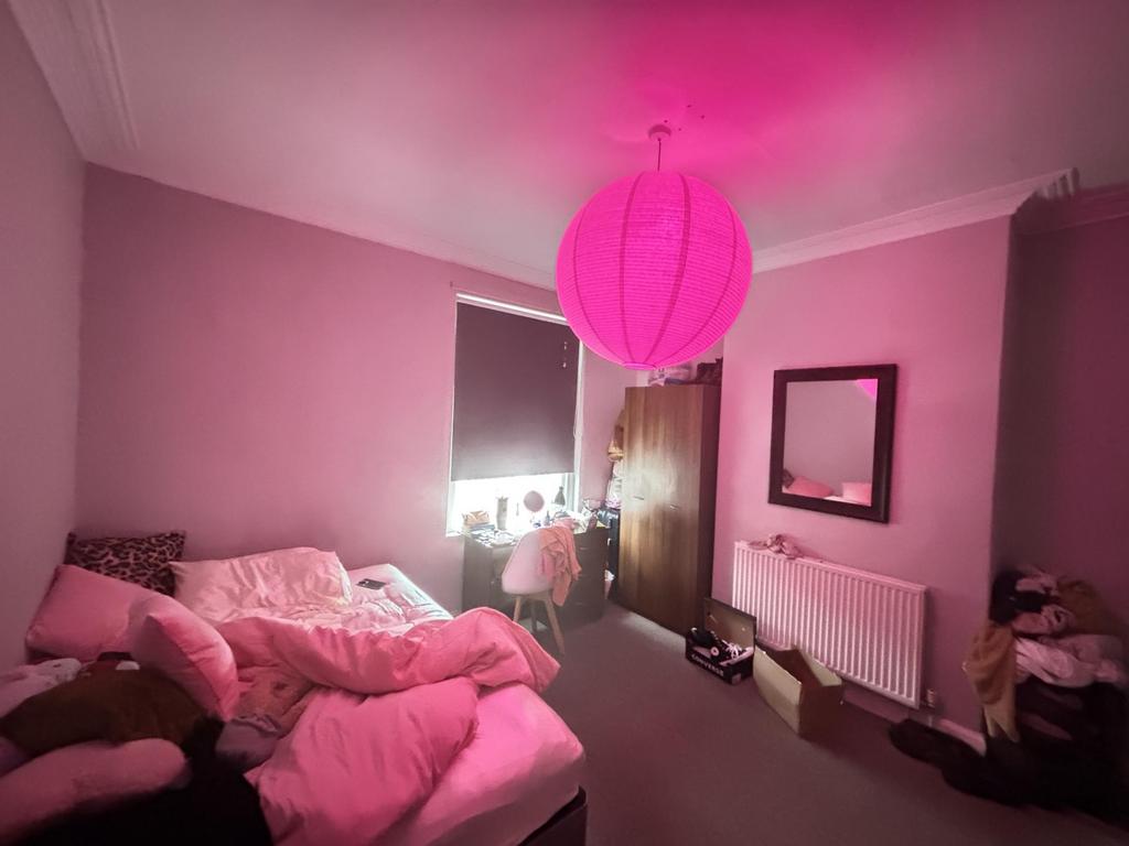 A cozy double bedroom with soft pink walls illu...