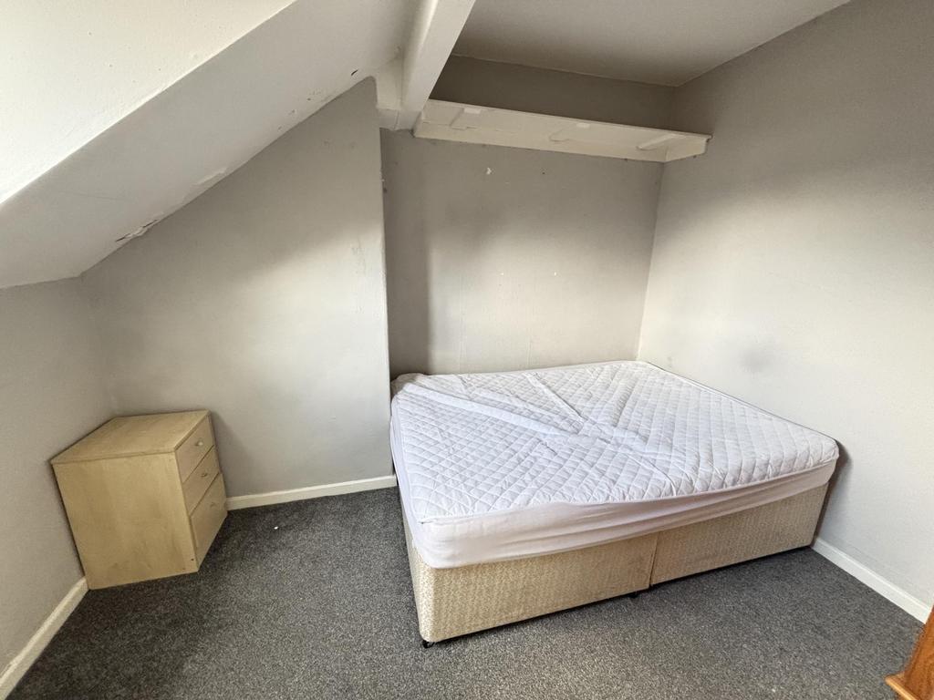 A cozy single bedroom with a sloped ceiling, a ...