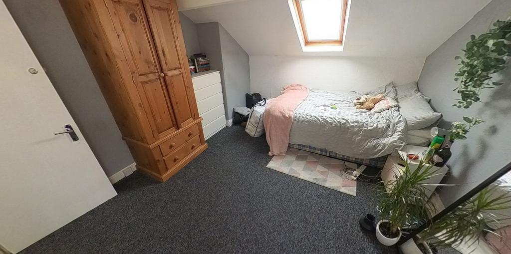 A cozy single bedroom featuring a bed with a pi...