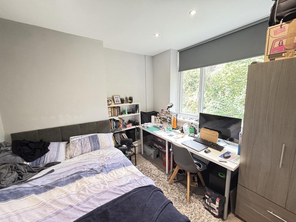 A well-lit bedroom featuring a large window all...