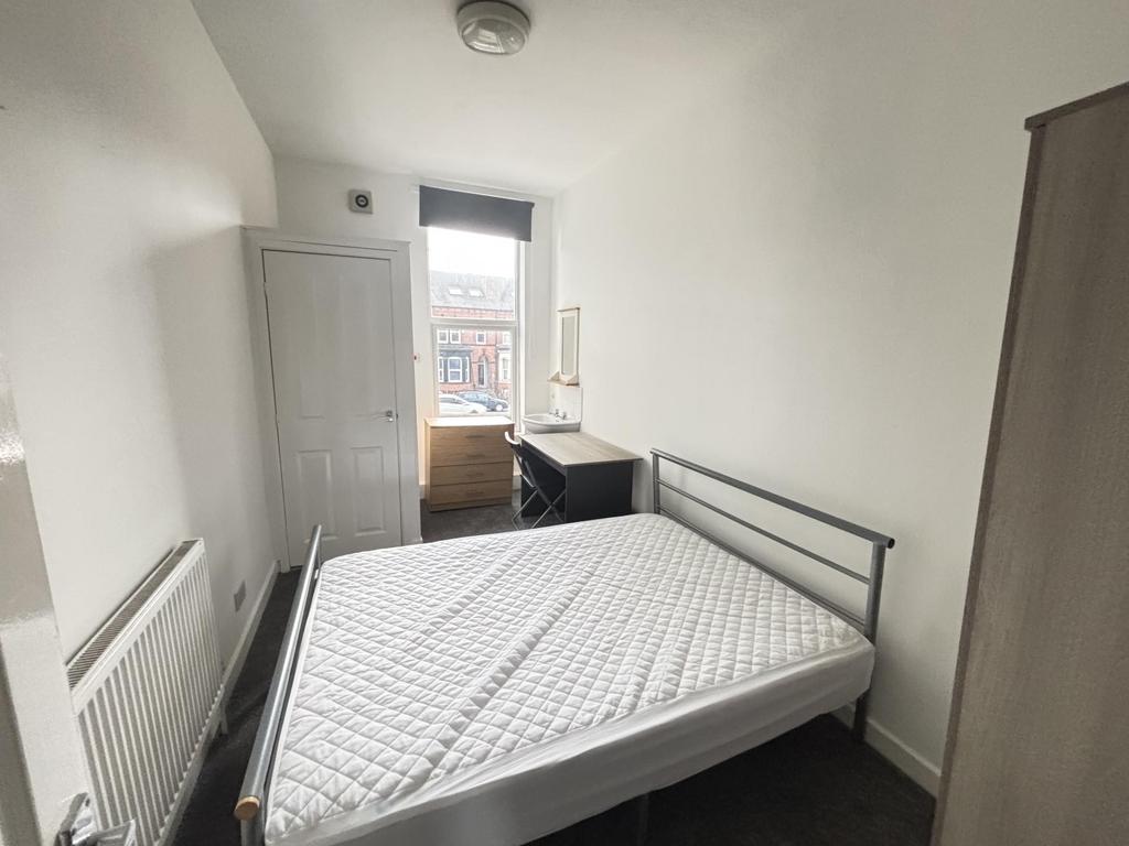 A bright and tidy bedroom featuring a comfortab...