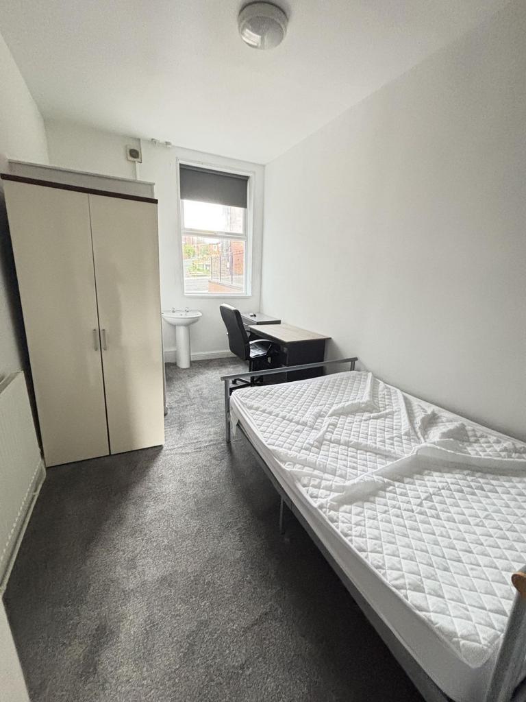A bright, tidy bedroom featuring a single bed, ...