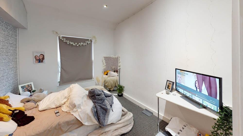 A cozy bedroom with a bed, some clothes on it, ...