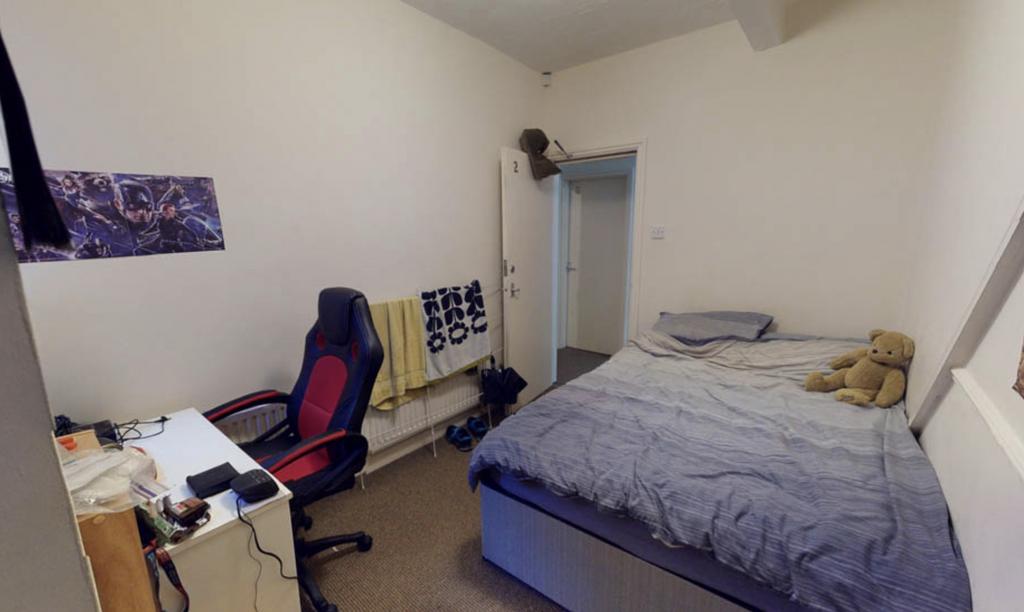 A modest single bedroom featuring a bed with mi...