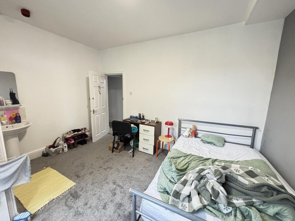 A cozy bedroom featuring a single bed, a desk, ...