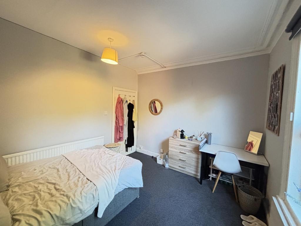 A bright and tidy bedroom with a neat bed, a sm...