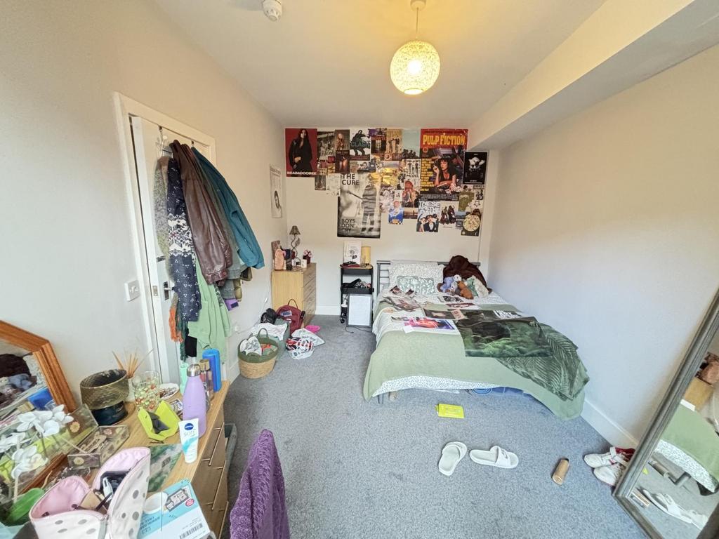 A cluttered bedroom with various items scattere...