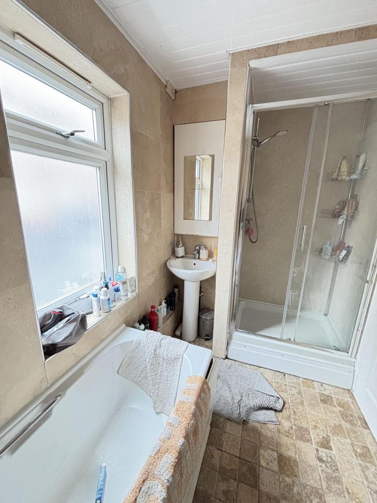A modest bathroom featuring a bathtub, a small ...