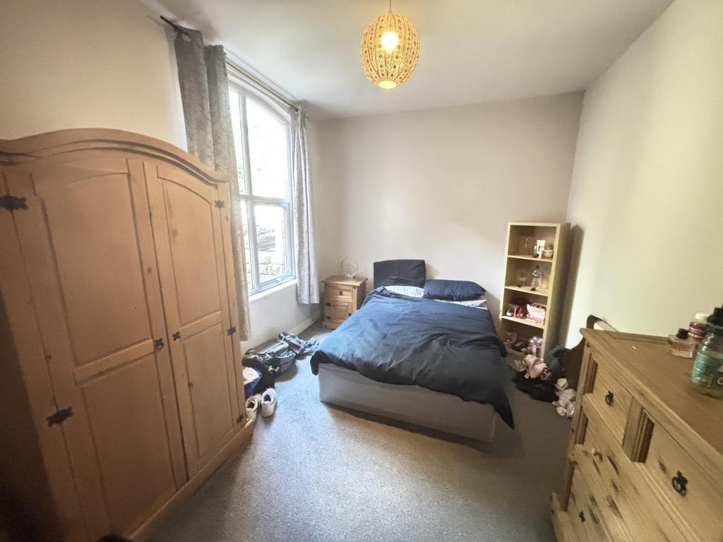 A cozy single bedroom featuring a bed and a sma...