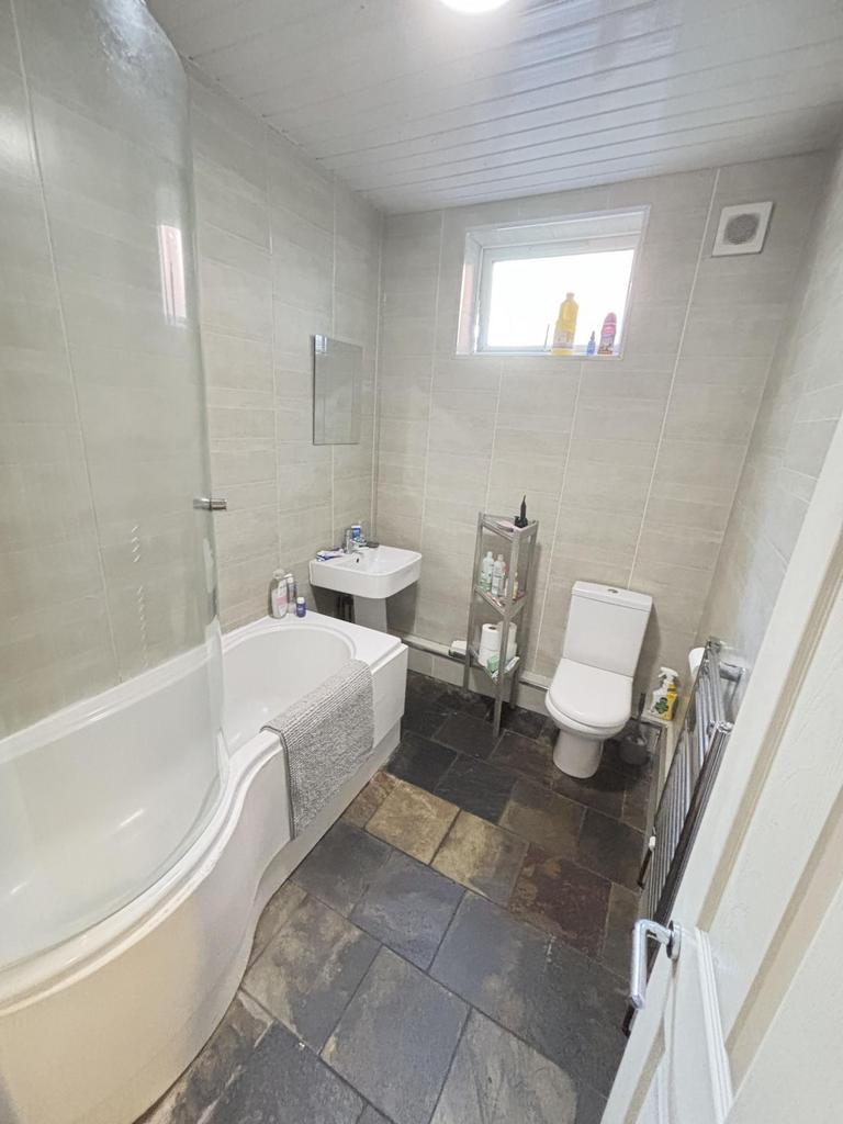 A clean and bright bathroom featuring a bathtub...