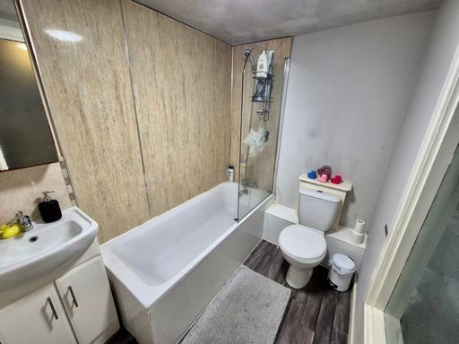 A bright and clean bathroom featuring a bathtub...