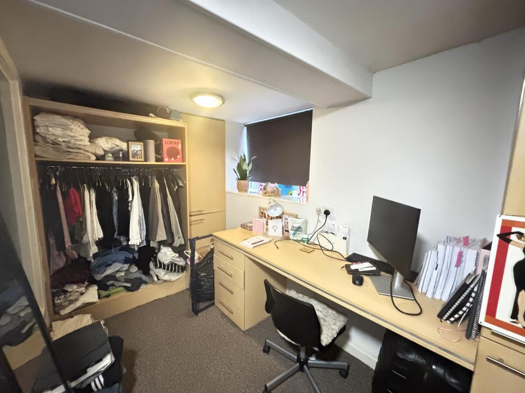 A well-organized bedroom featuring a desk with ...