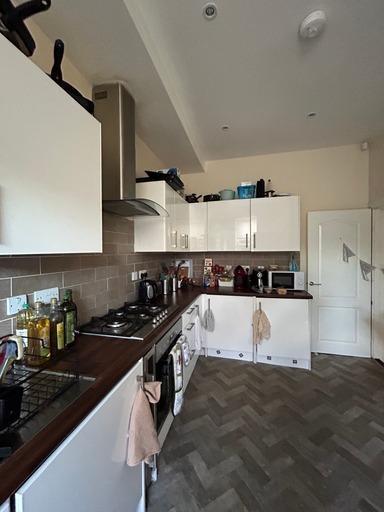 A modern kitchen featuring white cabinetry, a t...