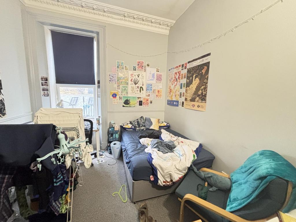 A cozy student bedroom with a bed, some study m...