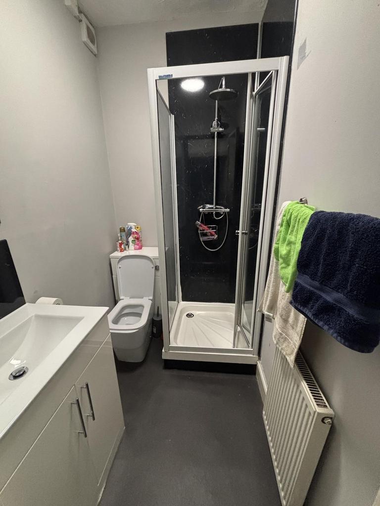 A modern, compact bathroom featuring a shower e...
