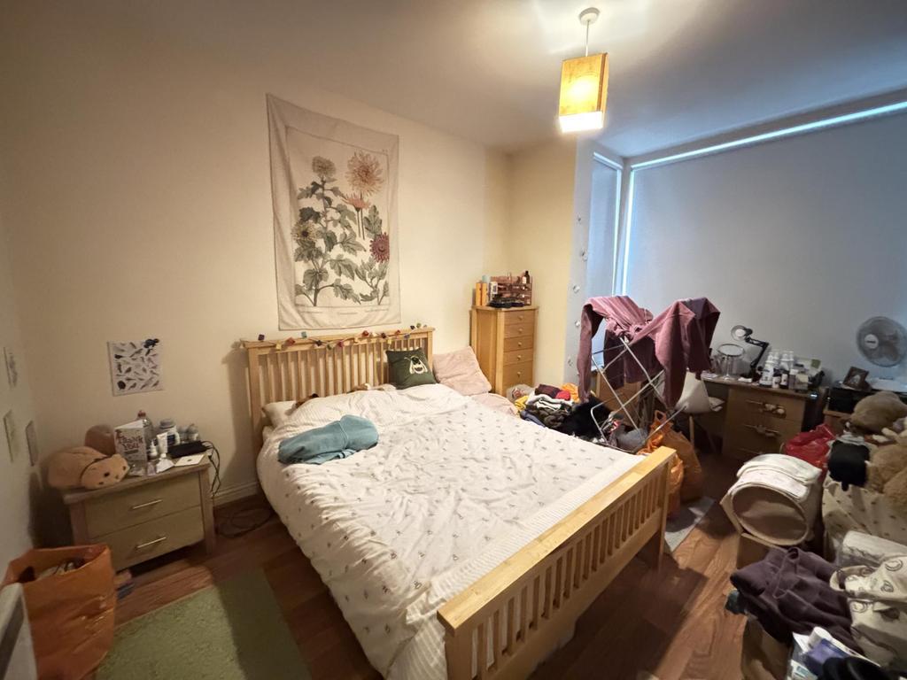 A cozy bedroom featuring a well-made bed, a woo...