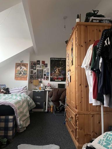 A cozy student bedroom featuring a bed, a woode...