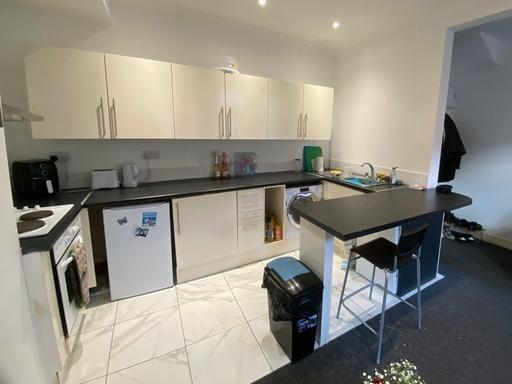 A modern, bright kitchen area featuring white c...
