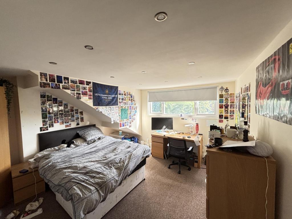 A well-lit, cozy bedroom featuring a comfortabl...