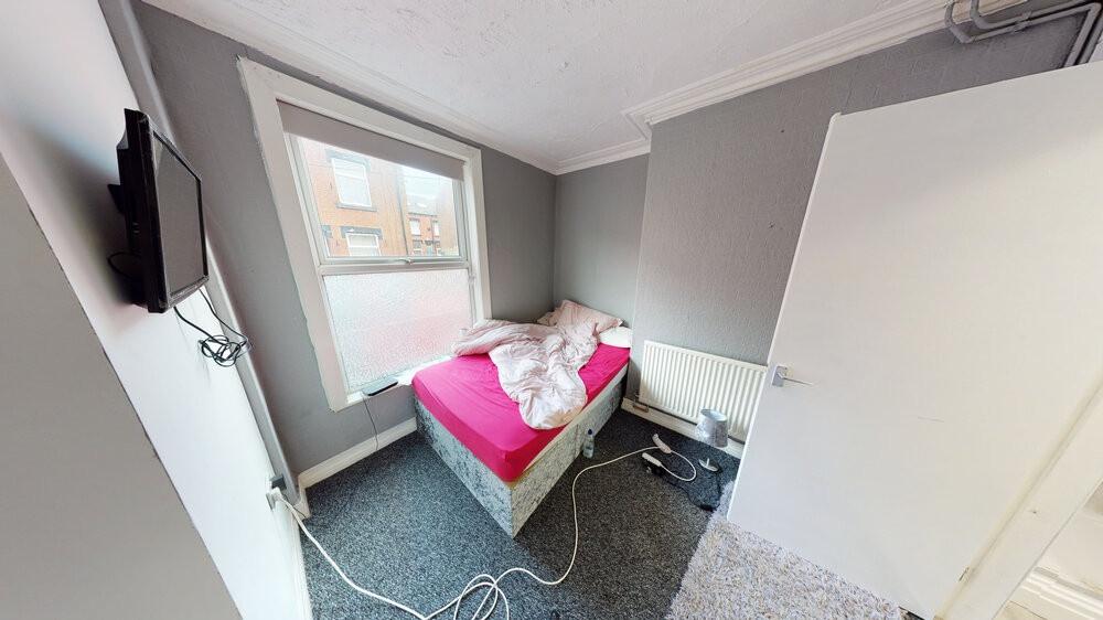 A cozy single bedroom featuring a bed with a br...