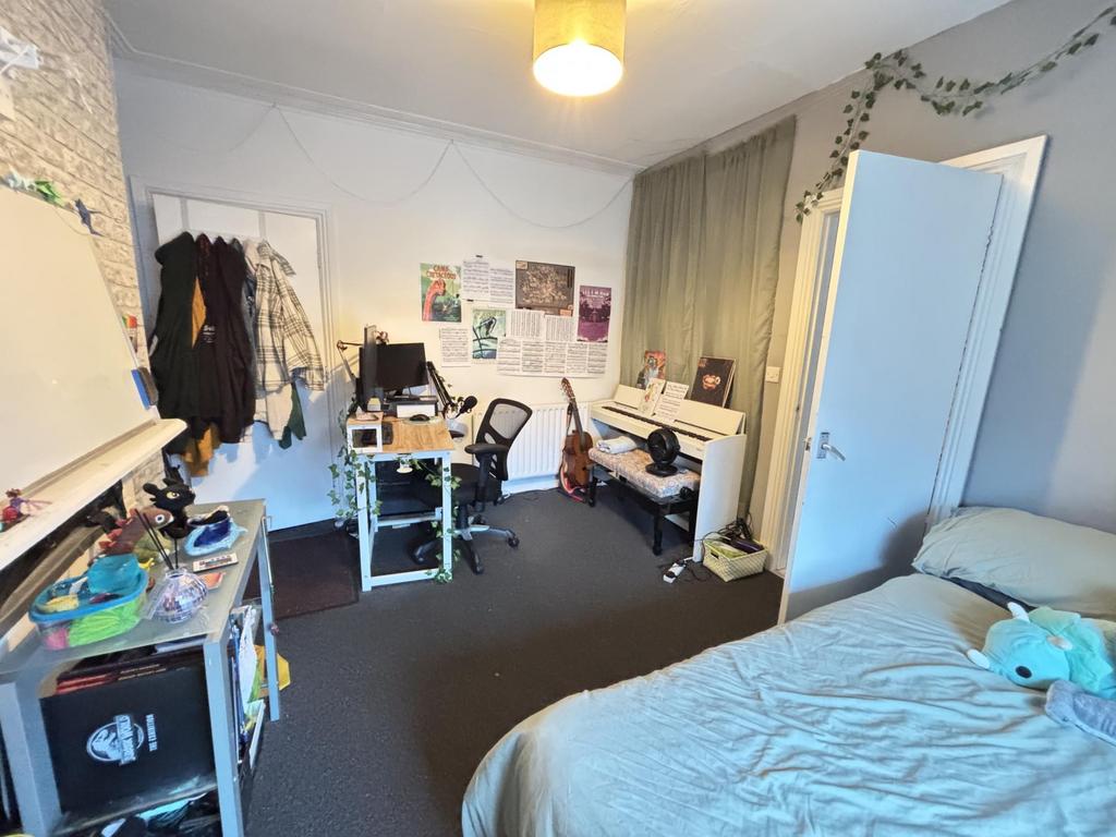 A cozy bedroom featuring a bed, desk, and wardr...