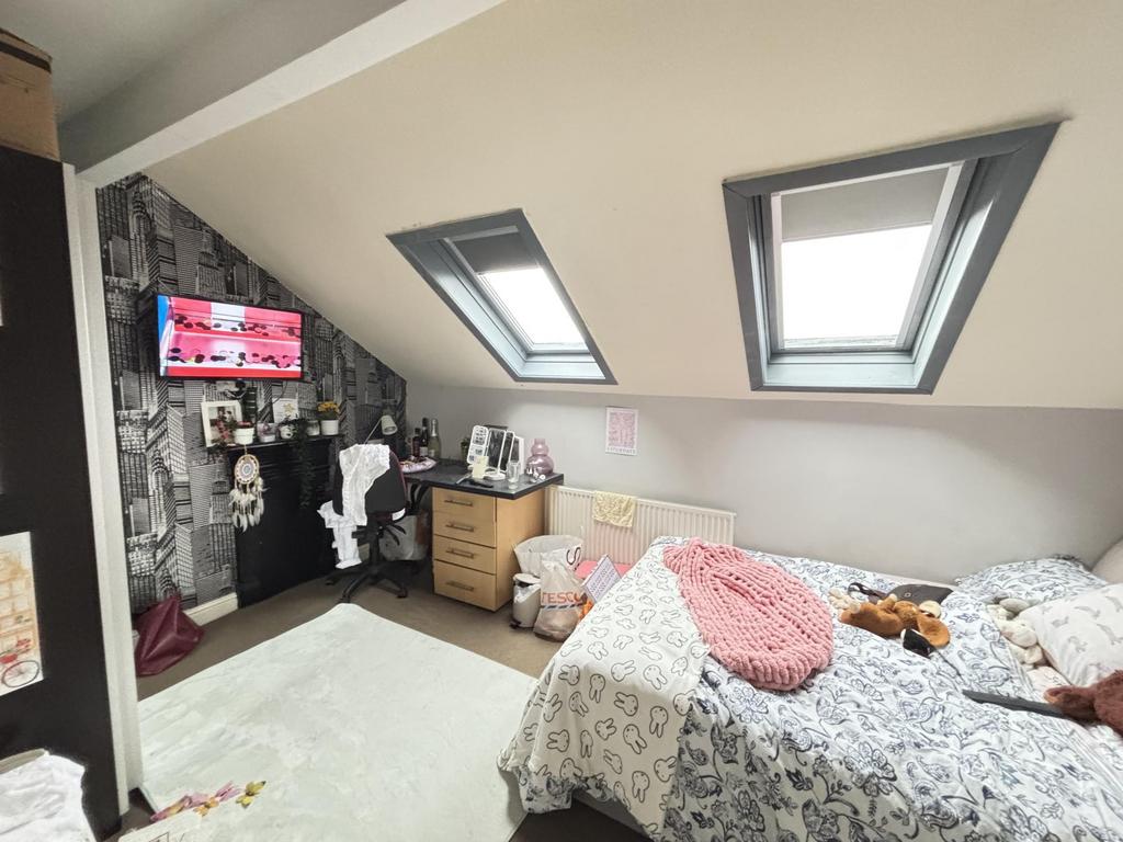 A bright and cozy bedroom with two skylight win...