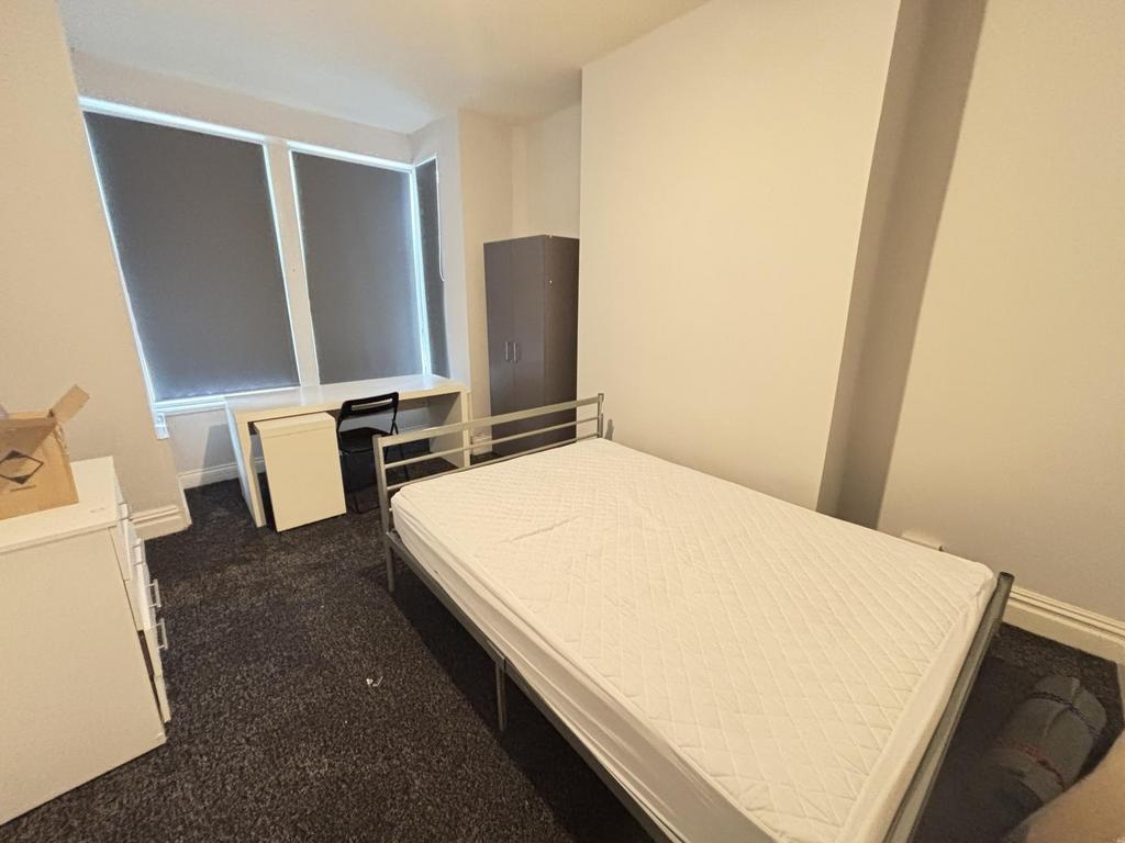 A simple, clean single bedroom with a window pr...