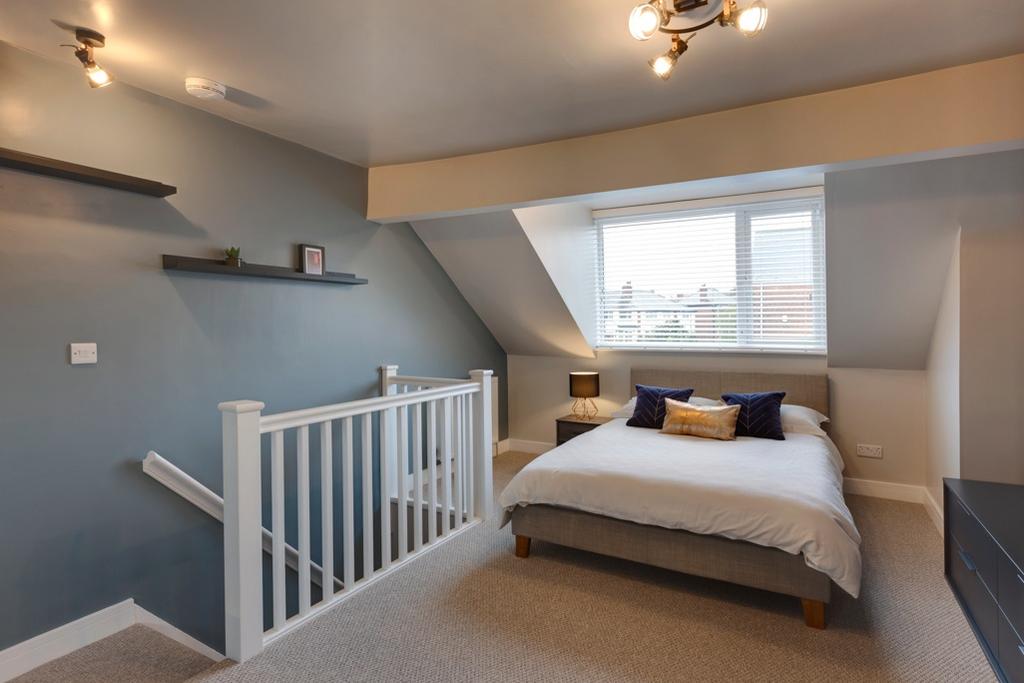 A modern, well-lit bedroom featuring a comforta...