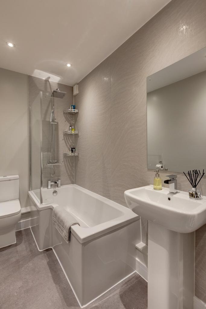 A modern, clean bathroom featuring a bathtub wi...