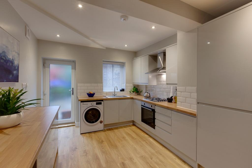 Modern fitted kitchen with light wood worktops,...