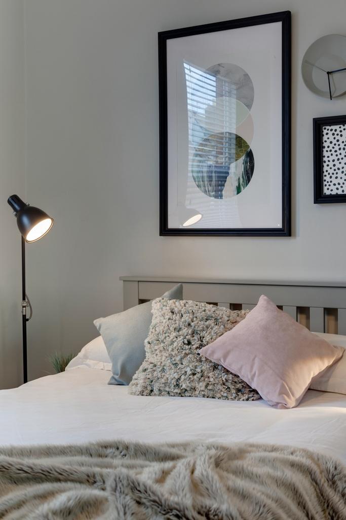 Bright, neatly styled bedroom with a comfortabl...