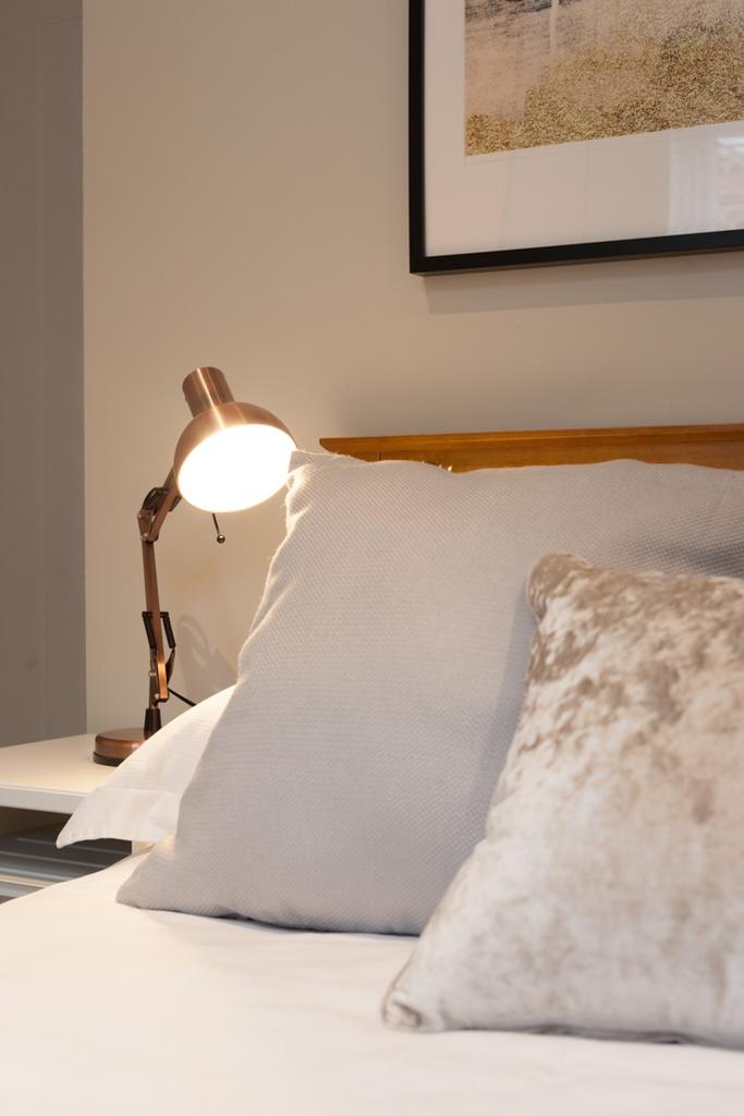 Stylish, neatly made bedroom with layered cushi...