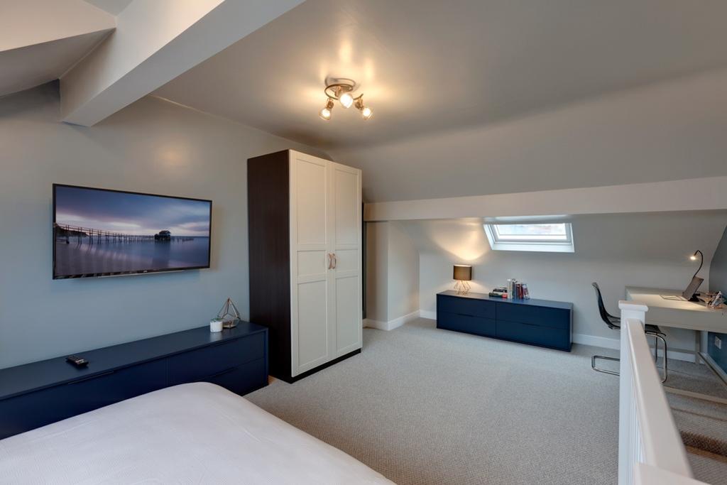 Bright, modern attic master bedroom with sloped...