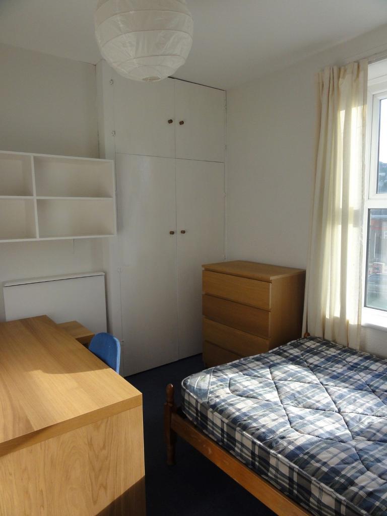 A modest single bedroom featuring a wooden bed ...