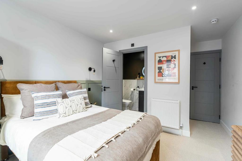 A bright and welcoming bedroom featuring a comf...