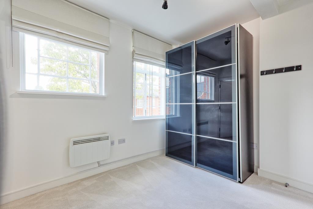 Carpeted main bedroom with wardrobe and two window
