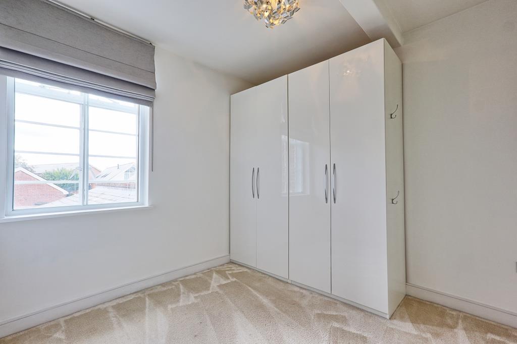 Carpeted 2nd bedroom with window and wardrobe