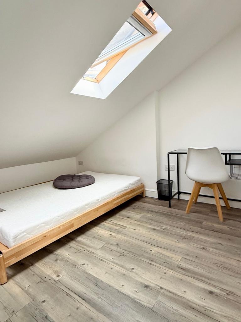 A simple, clean bedroom with a single bed under...