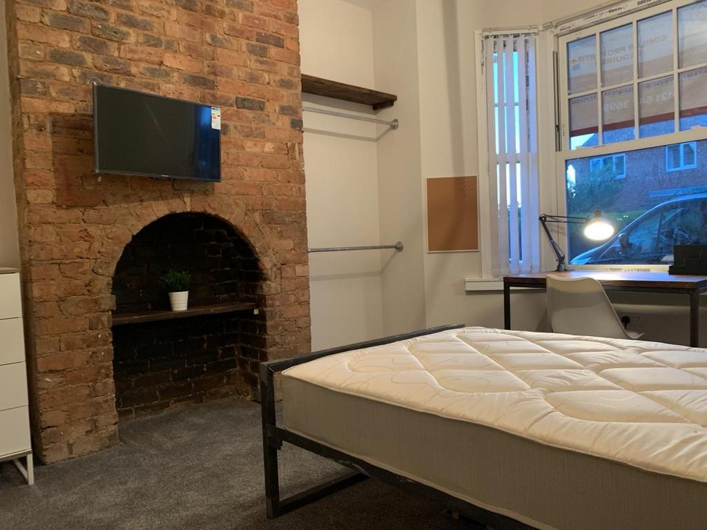 Spacious master bedroom with exposed brick feat...