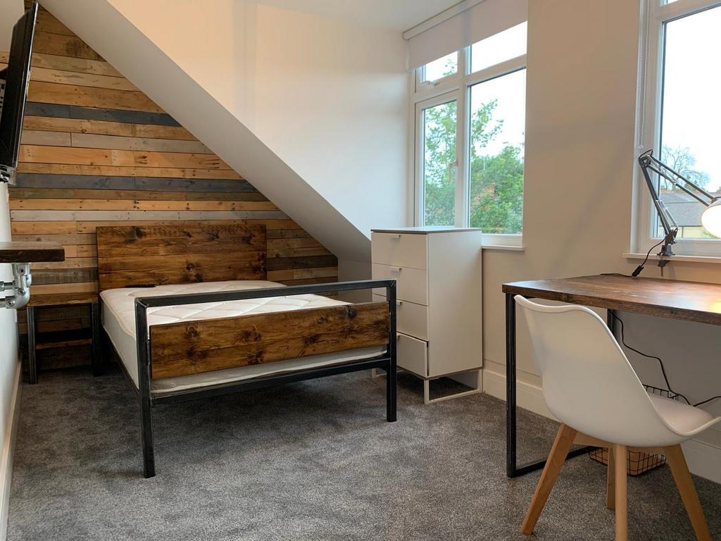 A modern bedroom featuring a wooden headboard a...