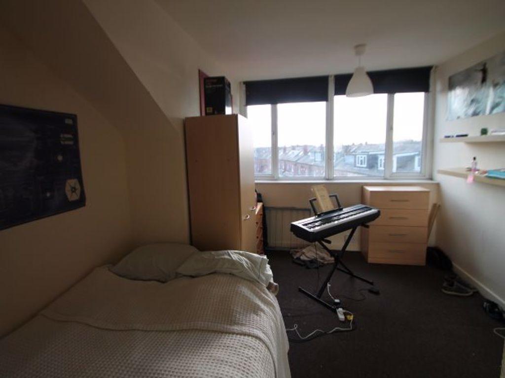 A well-lit bedroom with a single bed, a window ...