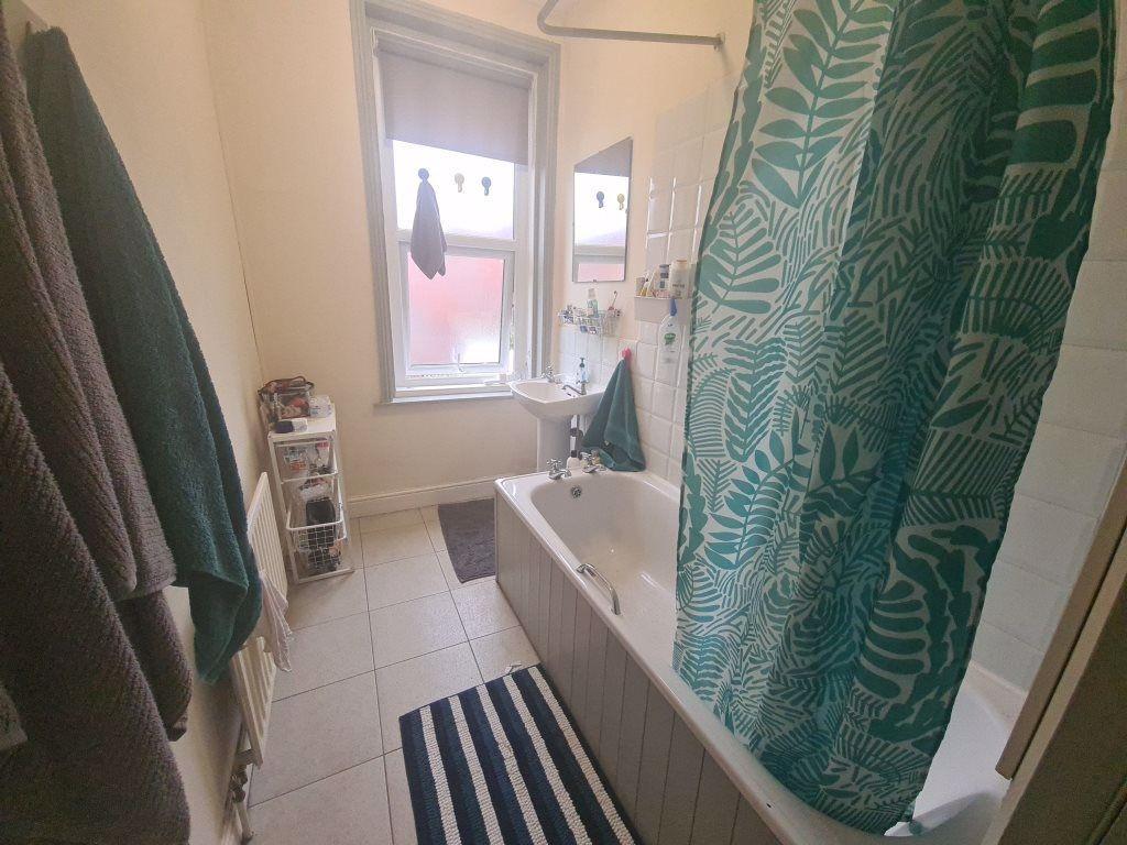 A clean bathroom featuring a bathtub with a sho...