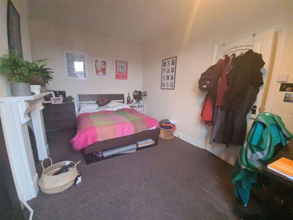 A cozy bedroom featuring a bed with pink and gr...