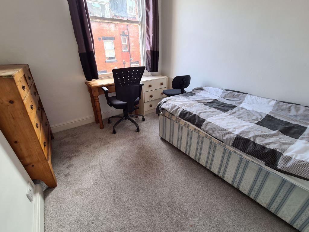 A cozy furnished bedroom featuring a bed, a des...